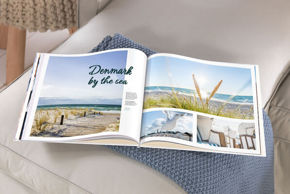 XL square photo book open to double page spread of beach images.