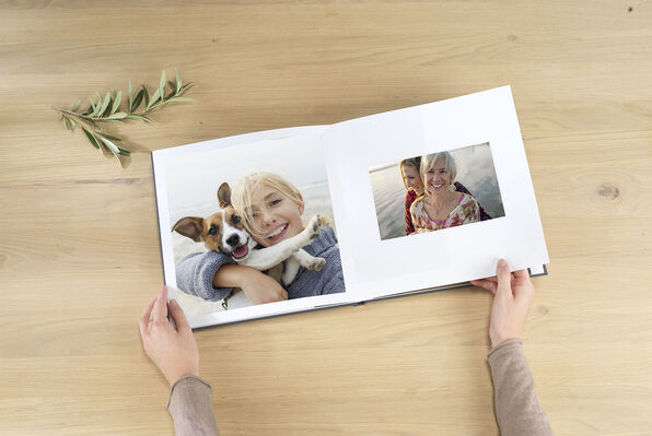 Square photo book open to pages with photos of a baby